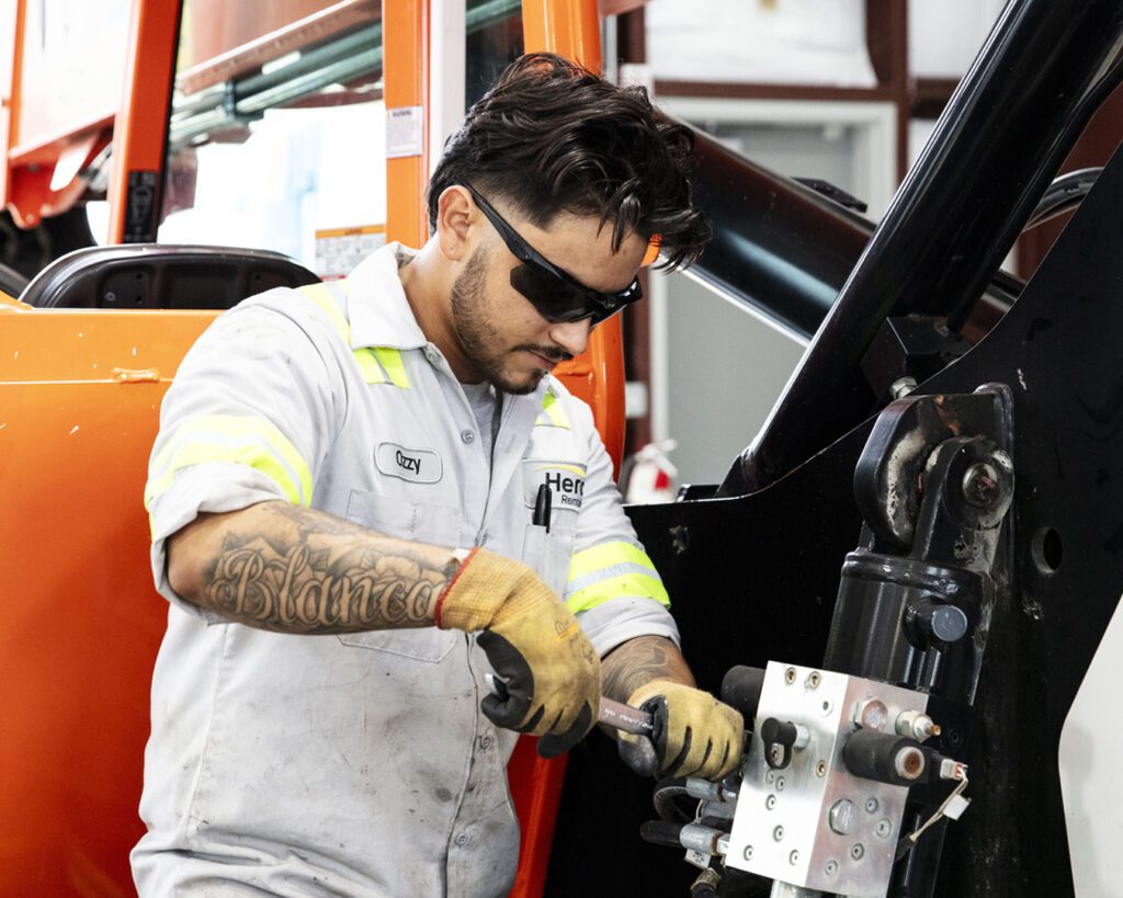 A mechanic works on a piece of equipment. A quality equipment rental provider can service your equipment safely and efficiently so you can spend more time on the job. 