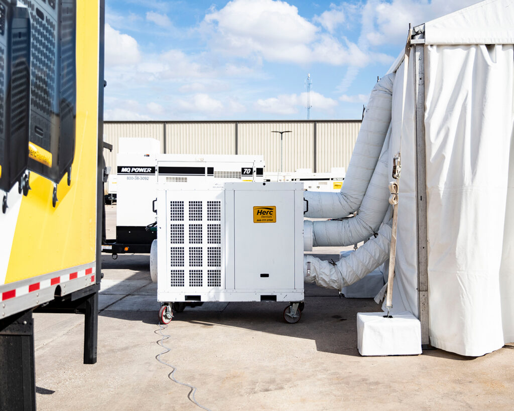 A portable AC unit is in use outside of a temporary building. The AC outlet plug must be compatible with the outlets within the facility. 