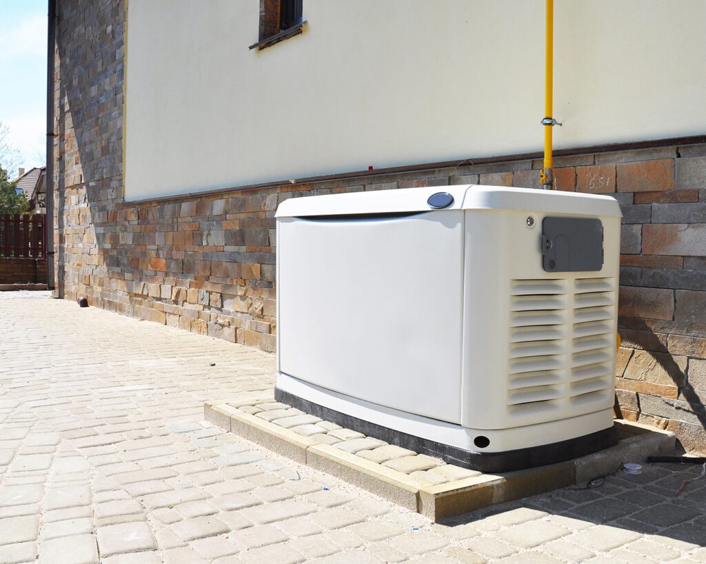 A standby generator is pictured in a permanent placement outside of a facility, on a concrete pad with a gas hookup.