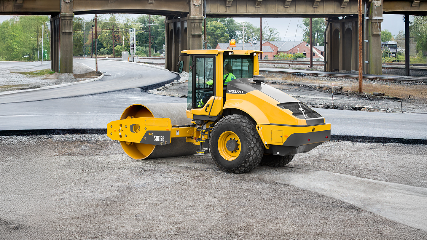 A ride-on asphalt roller moves across a space that is going to be paved.