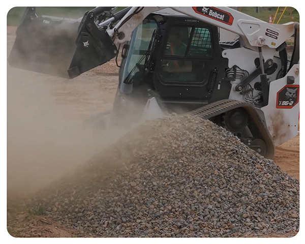 Skid steers -- like the one pictured next to a large, dusty pile of dirt -- can stabilize dirt, gravel and mulch to help in construction dust control. 